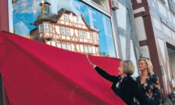 Effektvolle Spiegelung. Als Ilona Braun die verhüllte Boutique Fysel freischnitt, erschien im Schaufenster das benachbarte Rathaus.